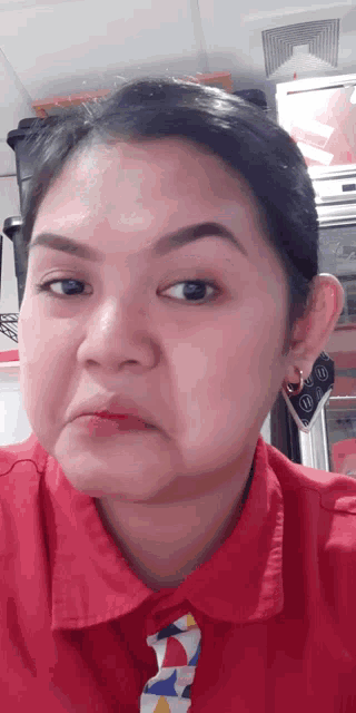 a woman wearing a red shirt and tie making a face