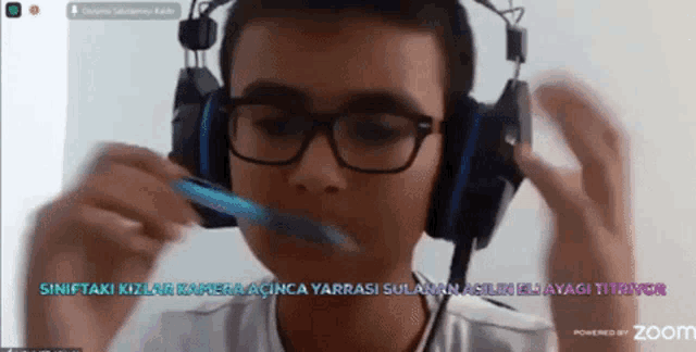 a boy wearing headphones and glasses is brushing his teeth on a zoom call