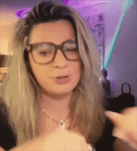 a woman wearing glasses and a necklace has a purple background