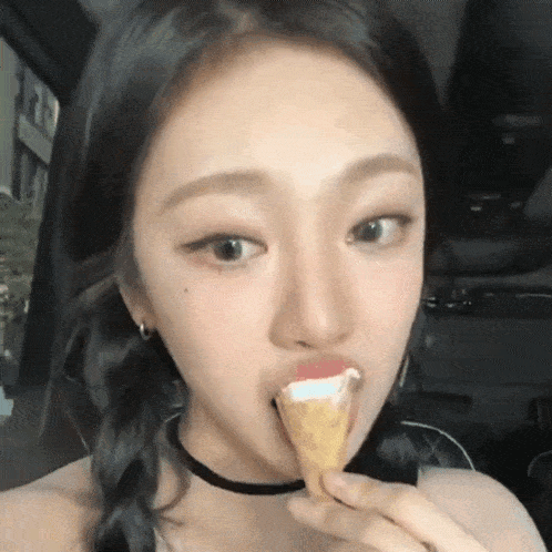 a young woman is eating an ice cream cone while sitting in a car .