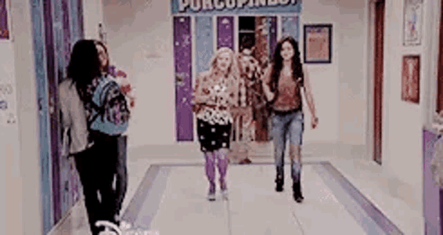 a group of young women are walking down a hallway .