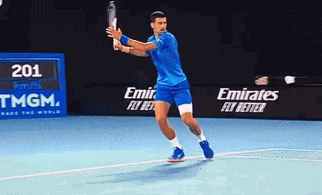 a tennis player is swinging a racket on a court with emirates advertisements