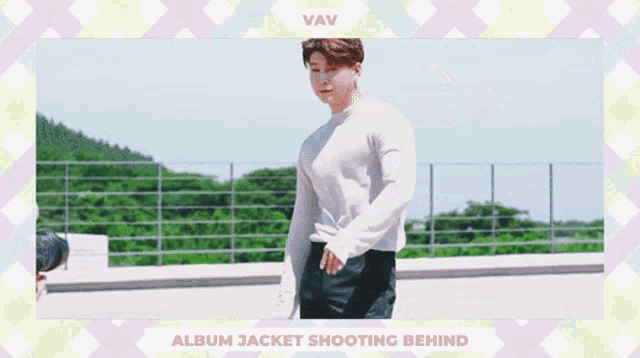 a man in a white sweater and black pants is standing in front of a fence and the words album jacket shooting behind