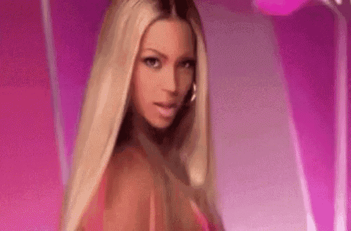 a close up of a woman with long blonde hair in a pink dress .