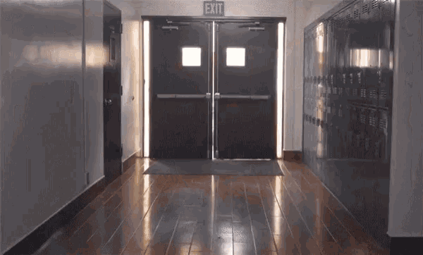 a hallway with lockers and an exit sign on the door