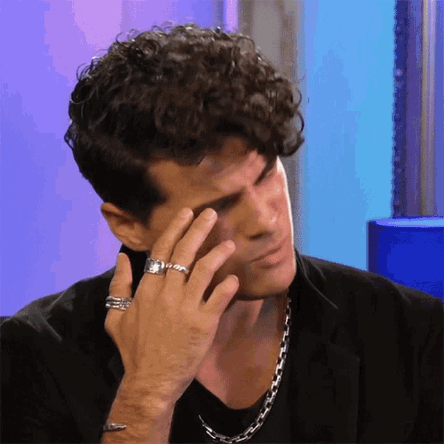 a man with curly hair has a ring on his left hand