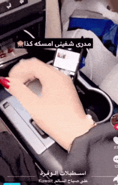 a woman with red nails is holding a cell phone in a cup holder