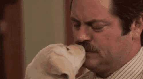 a man with a mustache is holding a small puppy in his arms .