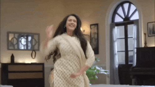 a woman in a white dress is dancing in a living room with a piano .