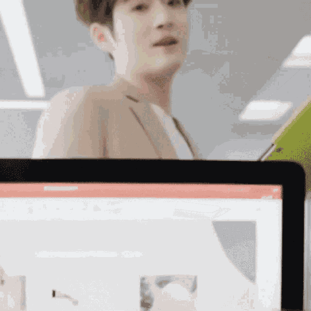 a man in a suit is sitting at a desk in front of a computer screen .