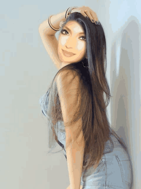 a woman with long hair is leaning against a white wall