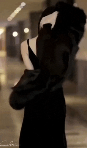 a woman in a black dress is standing in a hallway
