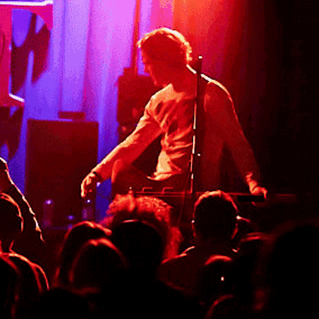 a man is playing a guitar in front of a crowd