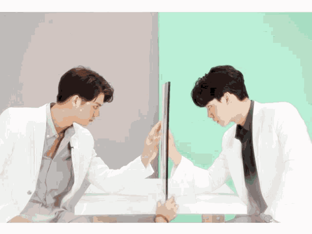 two men in white coats are looking at their reflections in a mirror
