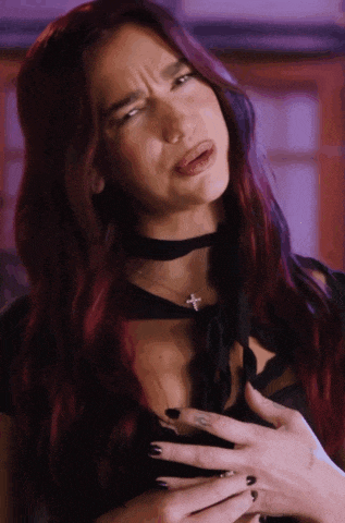 a woman with red hair and black nails is making a face