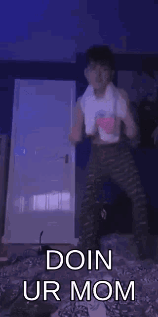 a young boy is dancing in a bedroom with a towel around his neck and says `` doin ur mom '' .