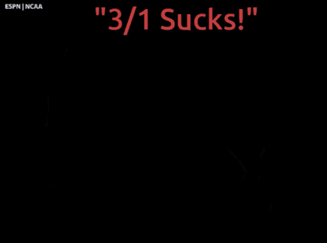 a young boy sitting in a stadium with the words " 3/1 sucks " on the screen behind him