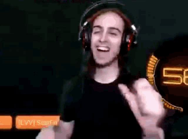 a man wearing headphones and a black shirt is dancing in front of a screen .