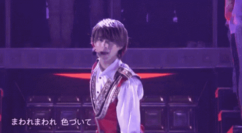 a young man in a red vest and white shirt is standing on a stage .
