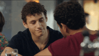 two men are sitting at a table and one of them has curly hair
