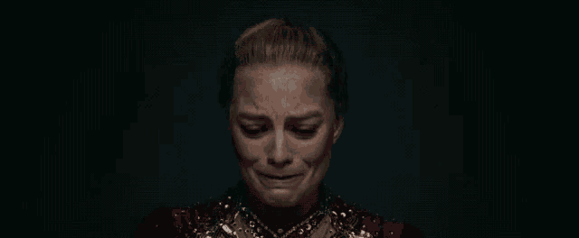 a close up of a woman 's face in a dark room with a tear coming out of her eye .