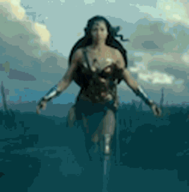 wonder woman is running through a field with her arms outstretched in a blurry photo .
