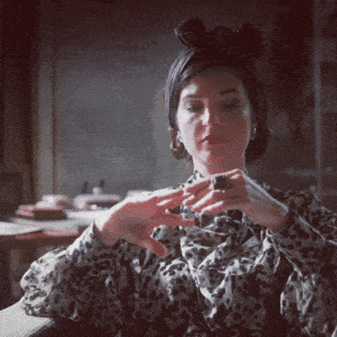 a woman wearing a leopard print shirt is holding a piece of chocolate