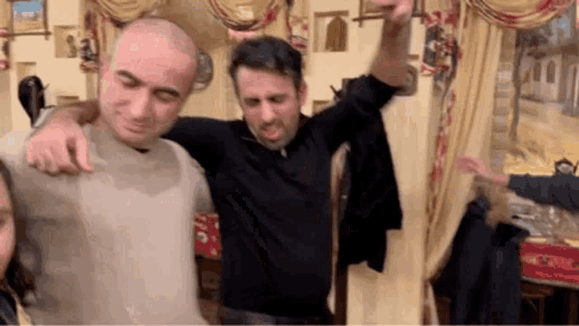 a group of men are dancing in a room with balloons in the background .