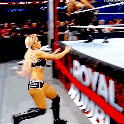 a woman is kneeling down in front of a royal rumble banner