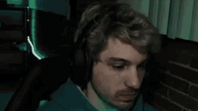 a man with a beard is wearing headphones and looking at the camera .