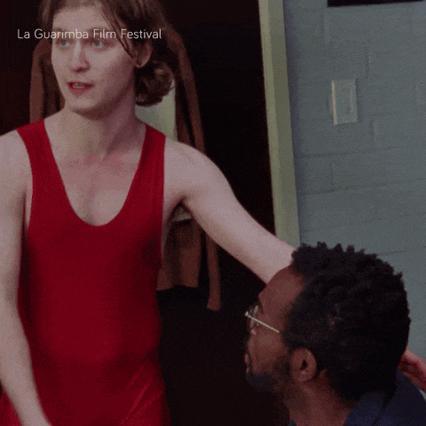 a man in a red tank top is standing next to another man with la guarimba film festival written on the bottom right