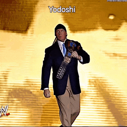 a man in a suit and tie holding a wrestling belt with yodoshi written on the bottom