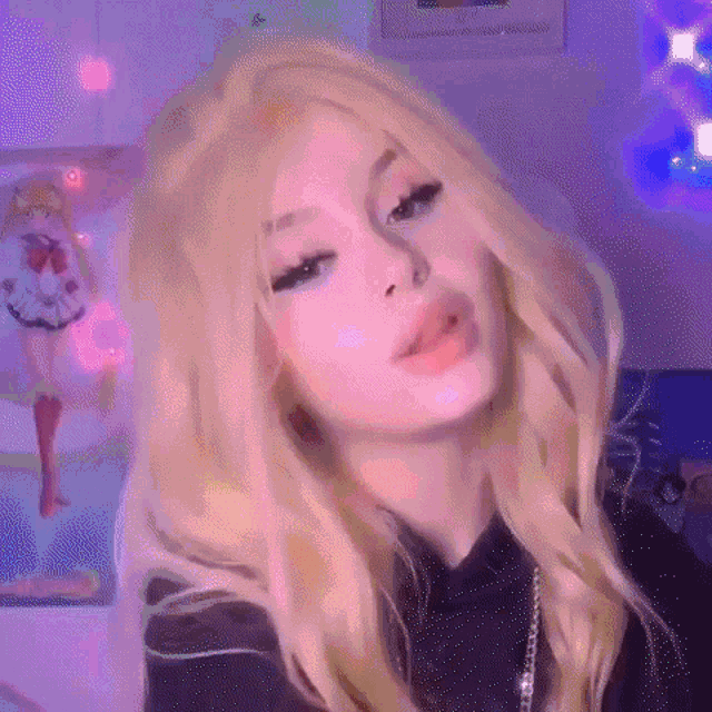 a girl with blonde hair is wearing a black shirt and a wig and making a funny face .