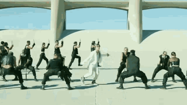 a man in a white suit is surrounded by a group of men in black pants .