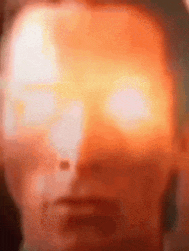 a close up of a man 's face with a bright orange light coming out of his eyes