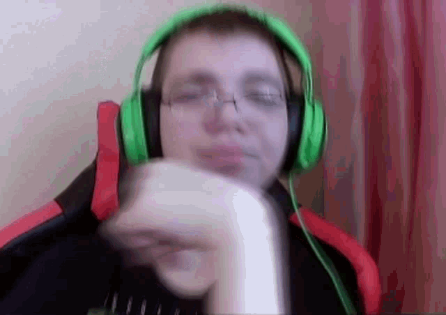 a man wearing green headphones and glasses is holding a white object .