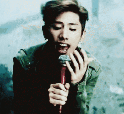 a young man is singing into a microphone with his mouth open