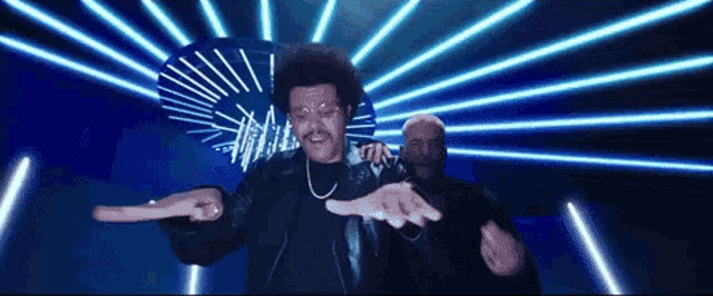 a man in a black jacket is dancing in front of blue lights