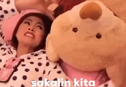 a woman is laying on a bed next to a stuffed animal and making a funny face .