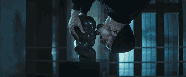 a man is holding a statue of a man 's head upside down