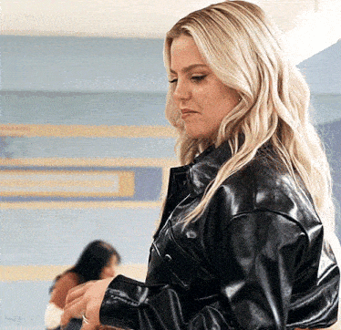 a woman in a black leather jacket looks down