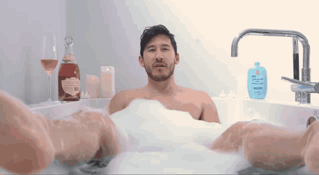 a man in a bathtub with a bottle of johnson 's baby lotion