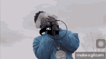 a man in a blue jacket is covering his face with money and a gun .