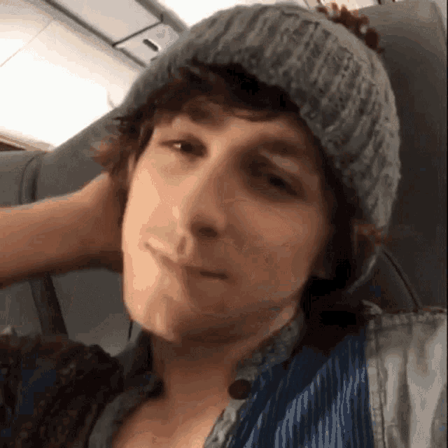 a young man wearing a gray beanie and a blue shirt