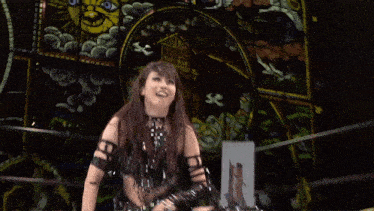 a woman in a black outfit is smiling and making a funny face