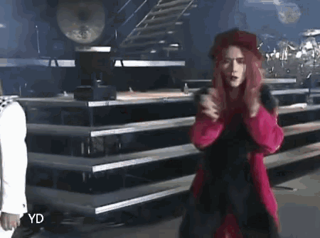 a woman with red hair and a red coat is standing on a stage .