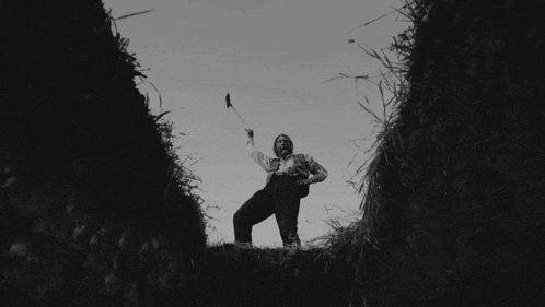 a black and white photo of a man holding a bird in his hand