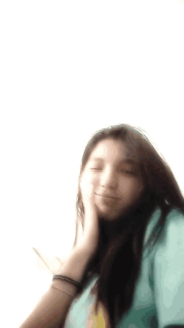 a blurry picture of a girl with long hair covering her face with her hand