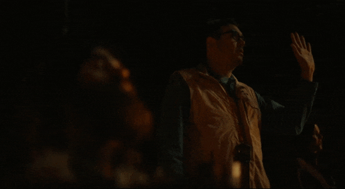 a man in a vest stands in the dark with the words what the fuck written above him