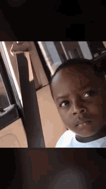 a young boy with a serious look on his face is sitting in a car